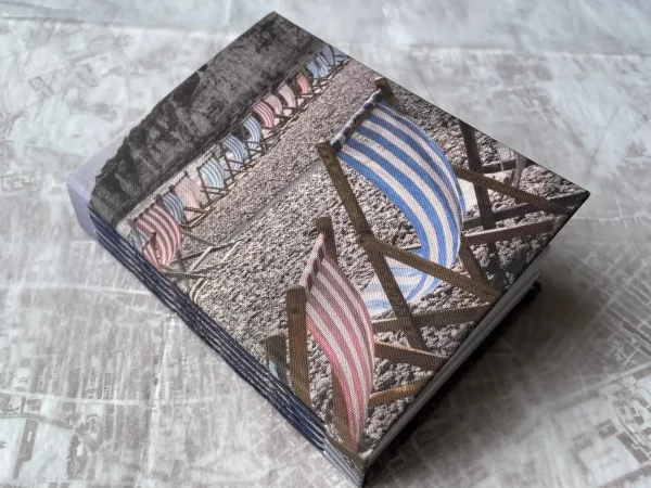 Cover of handmade book showing photo of striped blue and red deckchairs