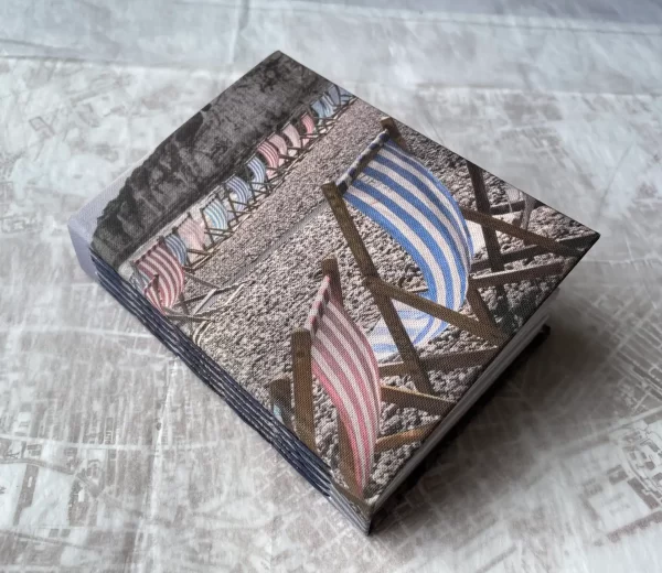 Cover of handmade book showing photo of striped blue and red deckchairs