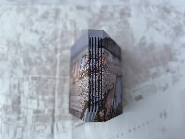 Spine of handmade book showing photo of striped blue and red deckchairs and chain stitching