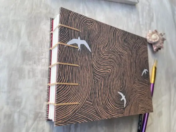 Brown and blue swirls with white Swifts watercolour sketchbook showing coptic spine